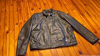 Front view of black leather Harley-Davidson motorcycle jacket laid flat