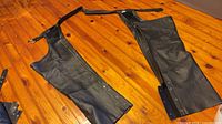 Full view of both chaps laid flat showing overall condition, zippers, snaps