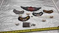 Overall lot showing patches, pins in cases, snap fasteners and measuring tape for scale