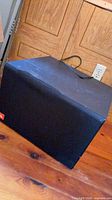 Front angled view of black JBL subwoofer cabinet