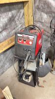 Welder on wheeled cart with torch and ground clamp visible
