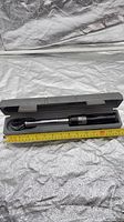 Torque wrench inside open storage case with tape measure showing length