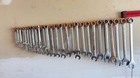 Full row of 26 Mastercraft combination wrenches hanging on board