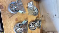 Overview of four metal caster wheels on wooden surface