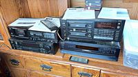 Four stacked black stereo components with papers and remotes