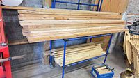 Stack of long lumber boards on rack, offcuts below