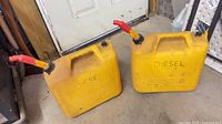 Both yellow diesel jerry cans side by side showing overall condition, spouts, caps