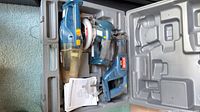 Open hard case showing handheld vacuum, circular saw, reciprocating saw, manuals