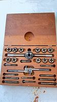 open wooden case displaying taps, dies and wrenches fitted in cut-outs