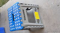 side view of grey Toolmaster folding step stool showing blue polka-dot top and brand logo