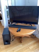 Sony 43-inch TV with soundbar on stand, subwoofer at side, remotes on soundbar