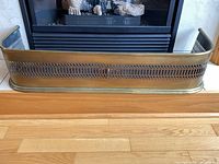 Front view of brass fireplace fender positioned at hearth