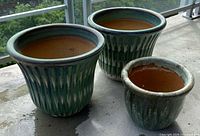 two large and one small green-glazed ribbed stoneware pots on balcony