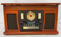 Front view of Victrola wooden turntable stereo showing speaker grilles, analog dial, control panel, CD slot