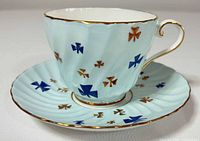 Oblique view of teacup on saucer showing exterior pattern and gilt trim