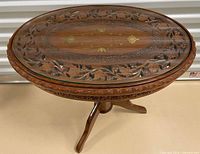 Oblique view showing carved rosewood table top with glass and tripod base
