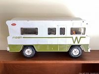 Left side view of pressed-steel Tonka Winnebago Indian camper showing white and green paint, windows and tires