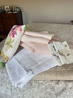 All pieces laid out on bed: beige quilt, pink coverlet, white skirt, floral pillow