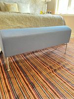 Angled front view of IKEA blue fabric bench at foot of bed