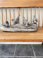 Full view of driftwood sculpture with four resin birds on bench