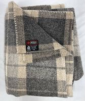 Folded plaid wool blanket showing label corner
