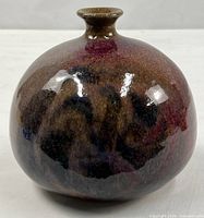 Front view of globular purple and black glazed pottery vase