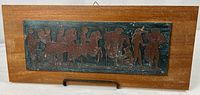 full view of wooden plaque with metal relief