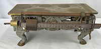 Side view showing brass platform, beam with sliding weight, ornate base and paw feet