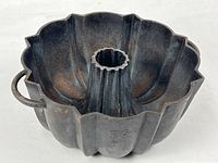 Full view of cast iron fluted pan showing handle and shape