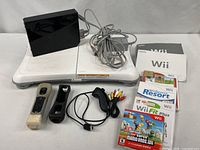 Overall lot showing console, balance board, controllers, cables, manuals and games