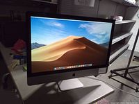 Front view of powered-on iMac displaying macOS desert wallpaper