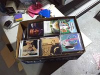 Top view of full copier-paper box showing multiple jewel-case CDs with visible album artwork