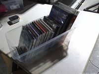 Overview of clear tote containing stack of jewel-case PC games and two DVD cases
