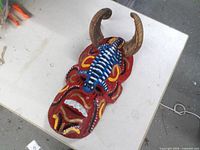Front view of painted wooden devil mask with horns