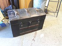 Front view of hump back trunk showing wood slats, embossed panels, hardware