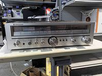 Front view of Kenwood receiver showing dial, knobs, and brand