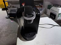 Front view of Keurig brewer showing logo, brew head, water reservoir, drip tray