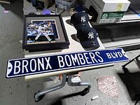 Lot overview with Bronx Bombers sign, signed photo in frame, two Yankees caps