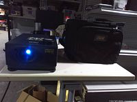 Projector powered on next to carry case