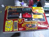 Front of opened retail box showing locomotive, rolling stock, track and controller through clear window