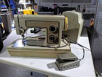 Left front view of sewing machine with foot pedal and case base