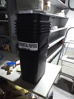 Stack of nine black plastic rectangular office trashcans