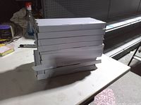 Stack of ten white cardboard keyboard boxes on table