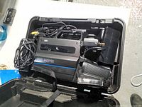 Open carrying case showing camcorder, battery, charger, cable