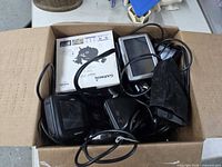 Open cardboard box showing multiple GPS units, cables, Garmin nüvi 255 box and pouch