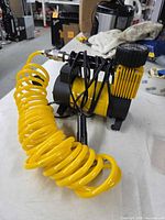 Side view of Cyclone MF-1040 compressor with yellow coiled hose and quick-connect fitting
