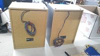 Rear view of both Panasonic speakers showing particle board backs, manufacturer labels, and attached wire leads