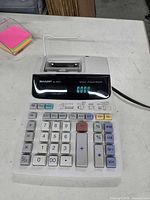 Top view of Sharp EL-387V printing calculator showing keypad, display, printer mechanism and AC cord