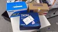 Three toner cartridge boxes on table: HP Q2683A, TN760 4-pack, Premium box