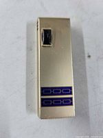 Front view showing gold-tone body, blue enamel bands, black ignition button